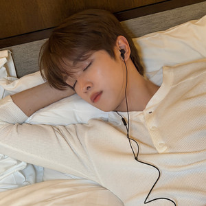 SUNGCHAN lying in bed with earphones